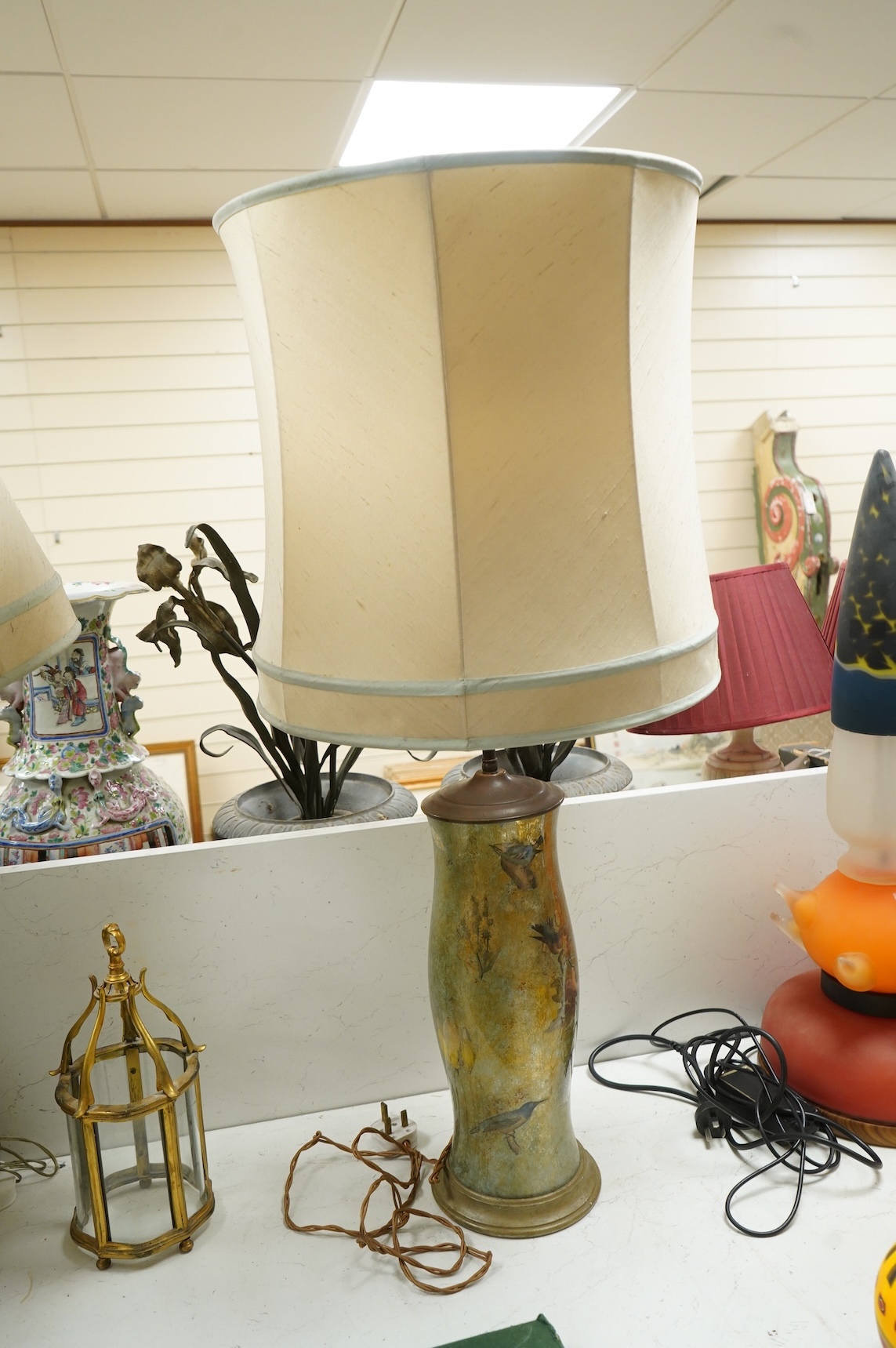 A pair of table lamps and shades, 92cm high, the lamps decorated in gold and green tones painted with birds and flowers, together with a small glass and brass hall lantern (3).